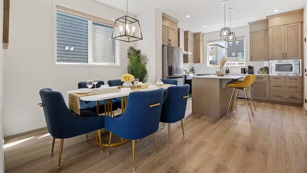 Una cucina moderna con mobili in legno, un'isola centrale e un'area pranzo con sedie blu e gambe dorate.