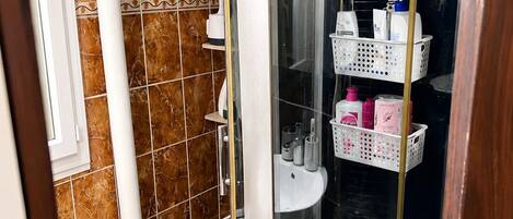 Une salle de bain avec des toilettes, un lavabo et une cabine de douche. Des paniers de rangement sont fixés au mur.