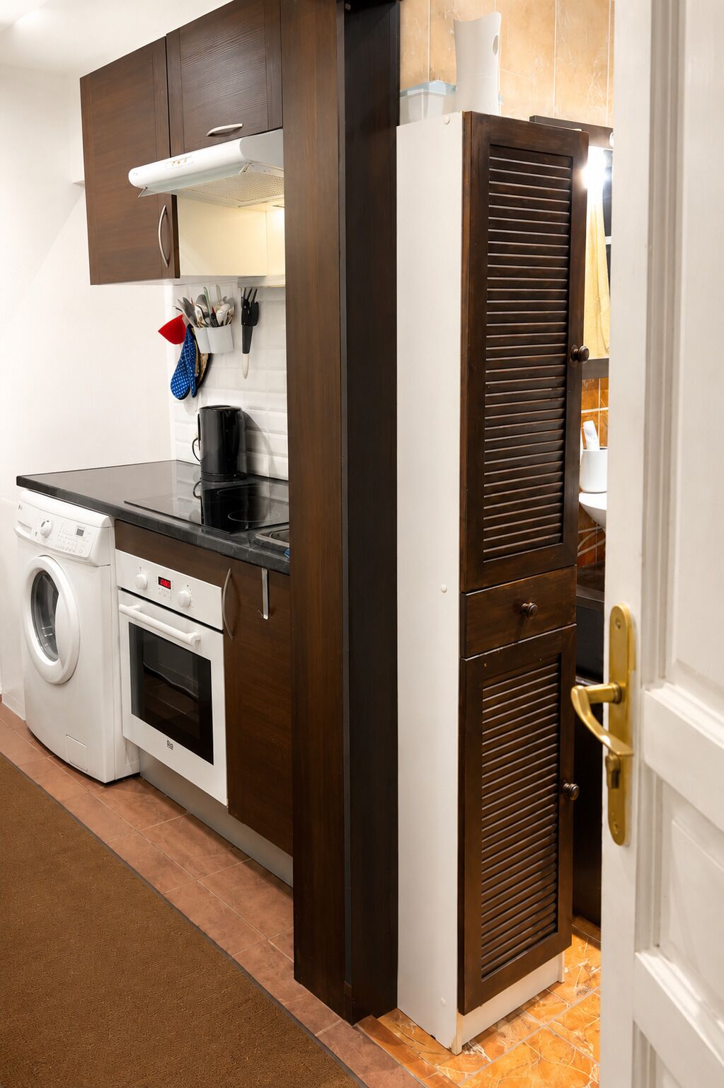 A compact kitchen with a washing machine, oven, and a built-in microwave.