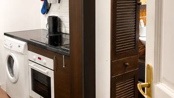 A compact kitchen with a washing machine, oven, and a built-in microwave.