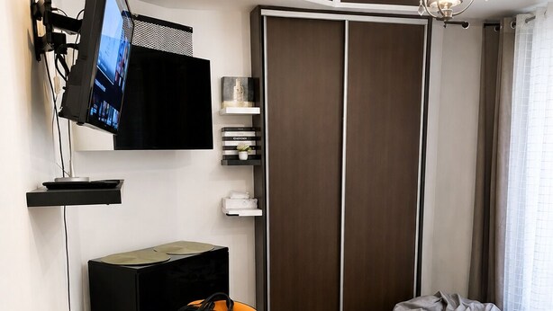 A modern room with a desk, a flat-screen TV, a laptop, a bean bag, and a sofa. - Charming and comfortable studio - Paris 14 (Paris)