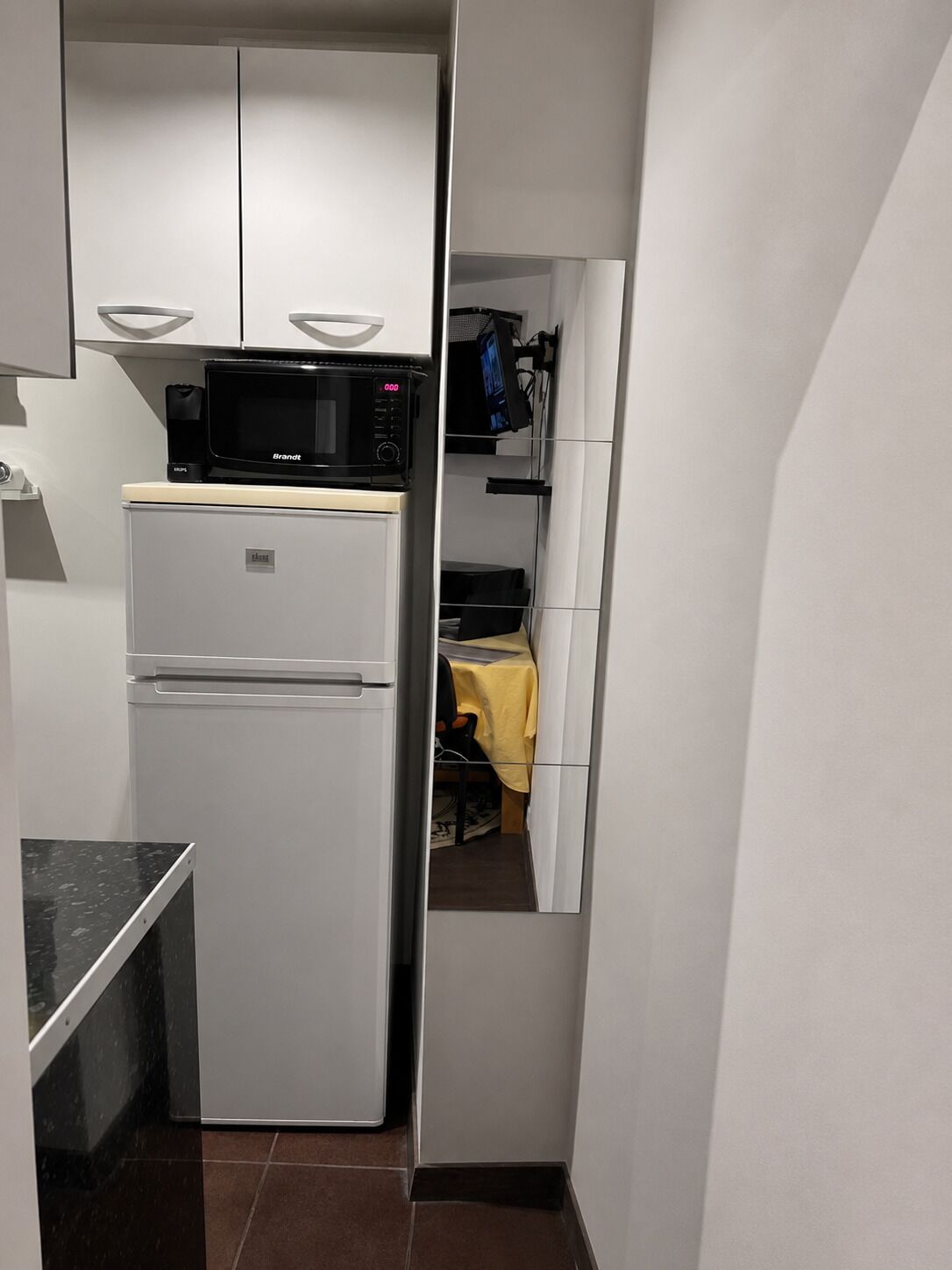 Eine kleine Küche mit einem weißen Kühlschrank, einer Mikrowelle und einem Spülbecken.