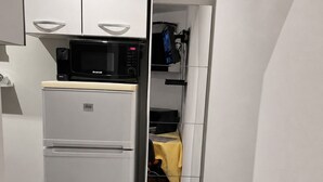 Une cuisine de taille réduite, avec un réfrigérateur blanc, un four à micro-ondes et un petit évier.