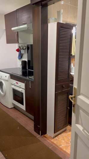 A compact kitchen with a washing machine, a stove, and a built-in oven. - Charming and comfortable studio - Paris 14 (Paris)