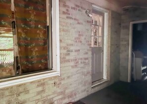 A room with a brick wall, a window with a floral curtain, and a door with a small shelf. - Perfect for Contractors: 2 mi from I-20 Bienvenidos Trabajadores! (North Augusta)