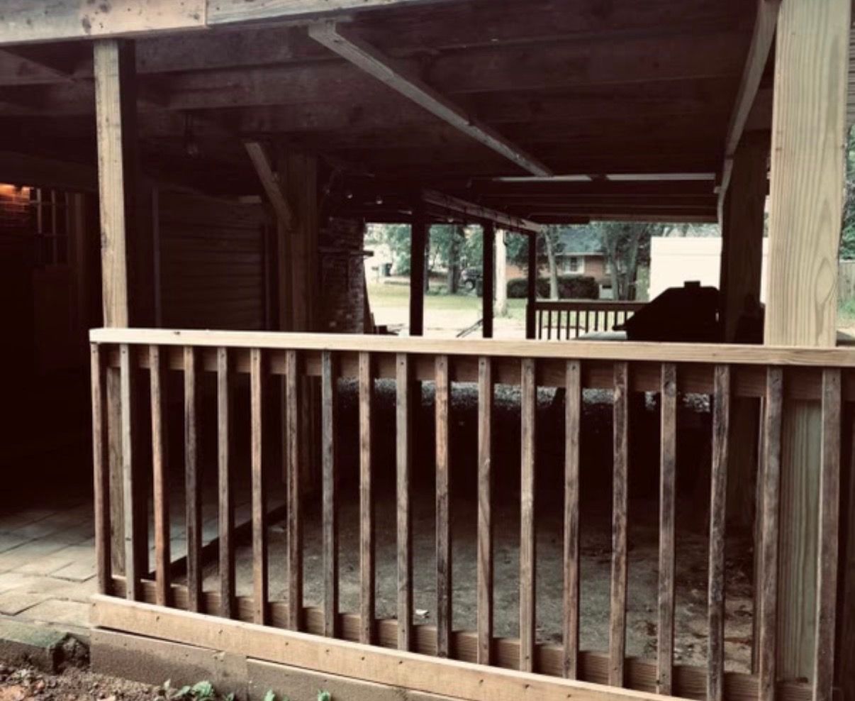 A wooden deck with a railing, a covered area, and a view of the outdoors.