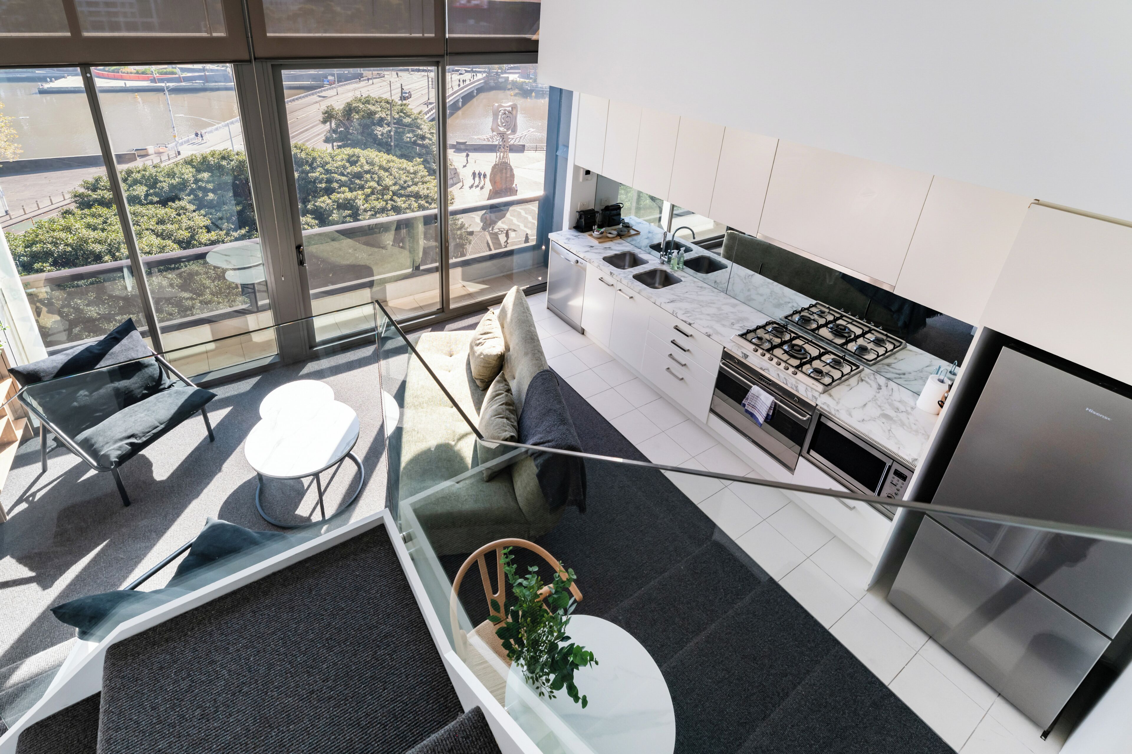 A modern kitchen with a gas stove, stainless steel appliances, and a view of a cityscape through large windows.