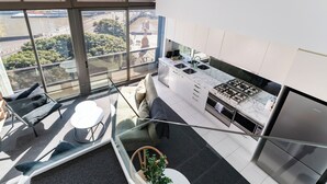 Una cocina moderna con estufa a gas, electrodomésticos de acero inoxidable y vistas a un paisaje urbano a través de amplias ventanas.