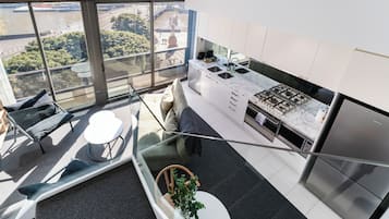 A modern kitchen with a gas stove, stainless steel appliances, and a view of a cityscape through large windows.