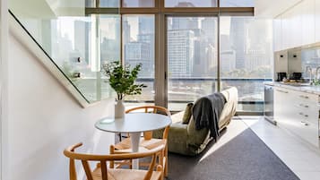 A modern living space with a dining area, a sofa, a staircase, and a kitchen.