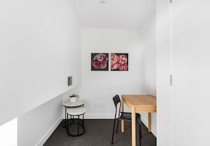 A small, modern room with a wooden table and two chairs, a small round table with a white chair, and two floral paintings on the wall. - Queensbridge Luxe - Balcony - Casino & Arts Precinct - Front Row - Parking (Southbank)