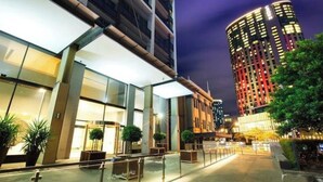 Un hotel moderno con fachada de vidrio, zona de estar al aire libre y una entrada bien iluminada.