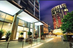 A modern hotel with a glass facade, outdoor seating area, and a well-lit entrance. - Riverfront | Balcony | Southbank Promenade | Arts Precinct | Parking | Crown (Southbank)