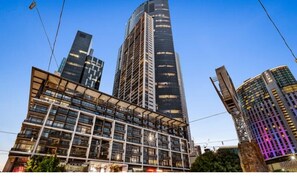 Ein modernes Gebäude mit Glasfassade, mehreren Stockwerken und einer markanten vertikalen Struktur.