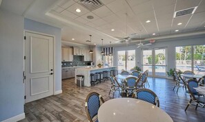 A spacious indoor area with a kitchen, dining area, and large windows. - Bright Lakeview Condo in Richmond Park with Garage (Naples)