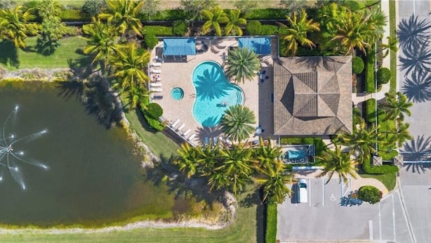 Ein Luftbild eines Resorts mit Schwimmbad, Palmen und einem Parkplatz.