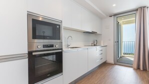 A modern kitchen with a built-in microwave, oven, and sink. - Infinity Blue by Atlantic Holiday (Camara de Lobos)
