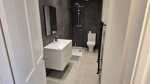 Ein modernes Badezimmer mit Waschbecken, Spiegel und Toilette, sowie einer Duschkabine.