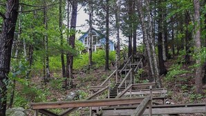 Eine hölzerne Treppe in einem bewaldeten Gebiet, die zu einem Gebäude mit blauem Dach führt.