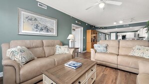 A living room with two beige sofas, a wooden coffee table, and a framed artwork on the wall. - Three Bedroom Oceanside Condo with Great Amenities (Ocean City)