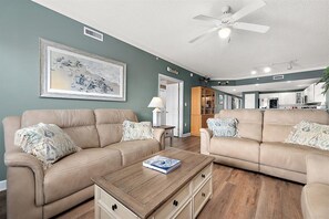 A living room with two beige sofas, a wooden coffee table, and a framed artwork on the wall. - Three Bedroom Oceanside Condo with Great Amenities (Ocean City)