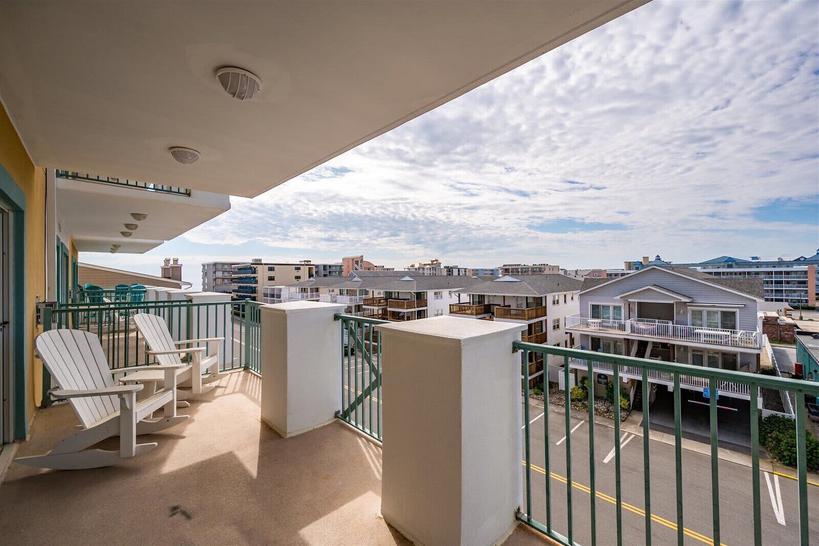 Un balcó amb cadires, vista a edificis residencials i cel blau.