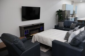 Un salon moderne doté d’un téléviseur à écran plat, d’une cheminée, d’un canapé et d’un coin repas avec des meubles de couleur bleu clair.