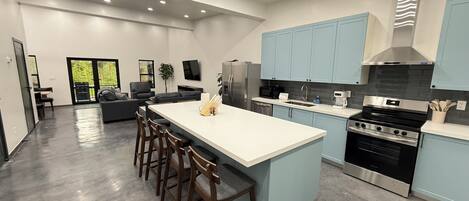 A modern kitchen with a central island, stainless steel appliances, and light blue cabinets.
