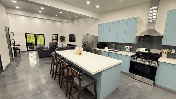Une cuisine moderne dotée d’un îlot central, d’appareils électroménagers en acier inoxydable et de meubles de couleur bleu clair.