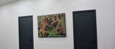 A room with a white wall, two black doors, and a framed picture of bears.