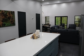Une cuisine moderne avec un plan de travail blanc, un range-couteaux et un coin repas comprenant une table et des chaises.