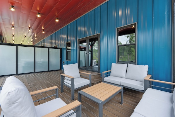 Un espace extérieur abrité, avec un mur bleu, des meubles blancs et une terrasse en bois.