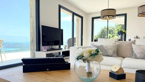 A modern living room with a TV, a sofa, a coffee table, and a vase of flowers. - Villa Sarra Di Pinarellu (Zonza)