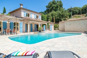 Una vila amb piscina, mobiliari d'exterior i un mur de pedra.