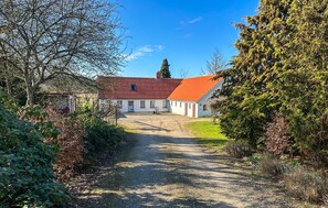 A rural property with a gravel driveway leading to a white building with a red roof, surrounded by trees and shrubs. - 3 bedroom gorgeous home in Silkeborg (Silkeborg)