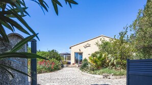 A building with a stone facade, a blue door, and a garden with various plants and flowers. - Villa Repose by Villa Plus (Argeliers)
