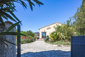 A building with a stone facade, a blue door, and a garden with various plants and flowers.
