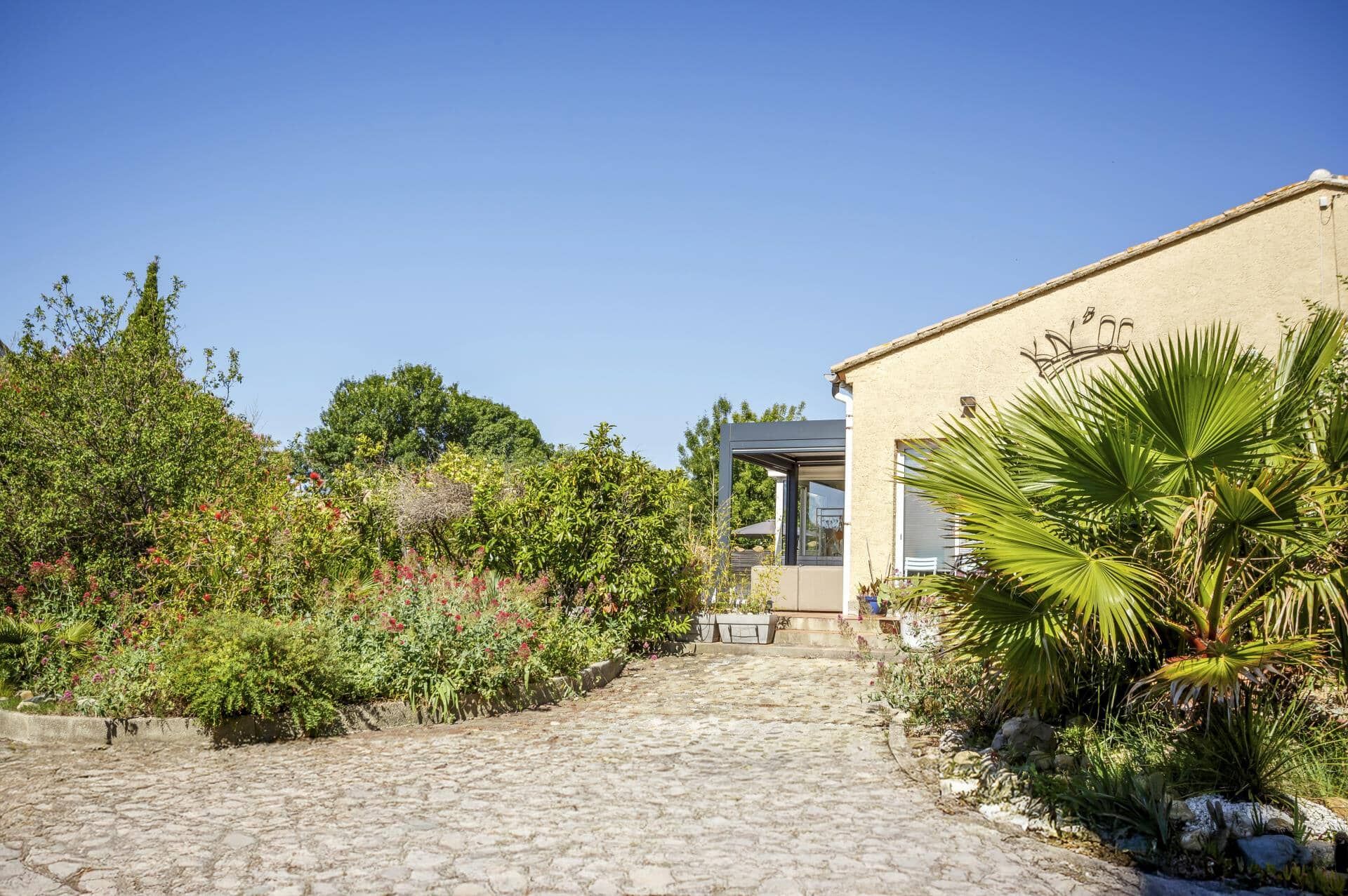 A cobblestone pathway leading to a modern building with a glass door entrance.