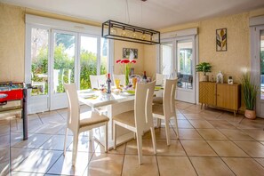A dining area with a table set for four, chairs, a chandelier, and a foosball table.
