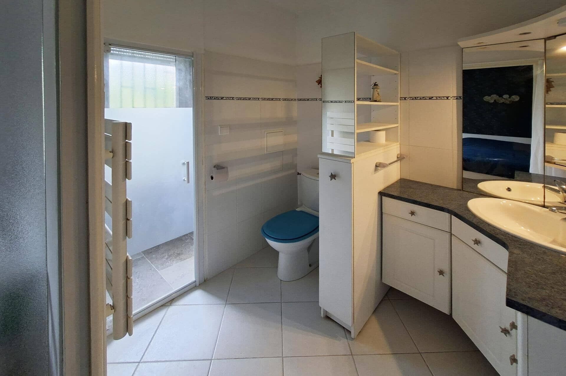 A bathroom with a toilet, a sink, a mirror, and a cabinet.