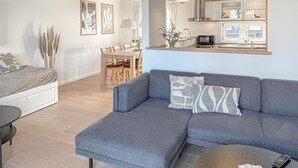Un salon moderne avec un canapé gris, une table à manger et un coin cuisine.