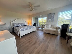 A bedroom with a bed, a chair, a couch, a desk, and a ceiling fan. - Sandy Pointe #114 ~ Beach, heated pool, Preserve (Holmes Beach)