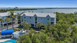 A multi-story hotel with balconies, a swimming pool, and a view of the water. - Sandy Pointe #114 ~ Beach, heated pool, Preserve (Holmes Beach)