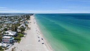 A coastal beach area with a long stretch of sandy beach, a few buildings, and a clear view of the ocean. - Sandy Pointe #114 ~ Beach, heated pool, Preserve (Holmes Beach)