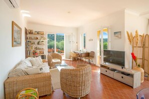 Ein geräumiges Wohnzimmer mit einer Couch, Sesseln, einem Fernseher und einem Bücherregal.