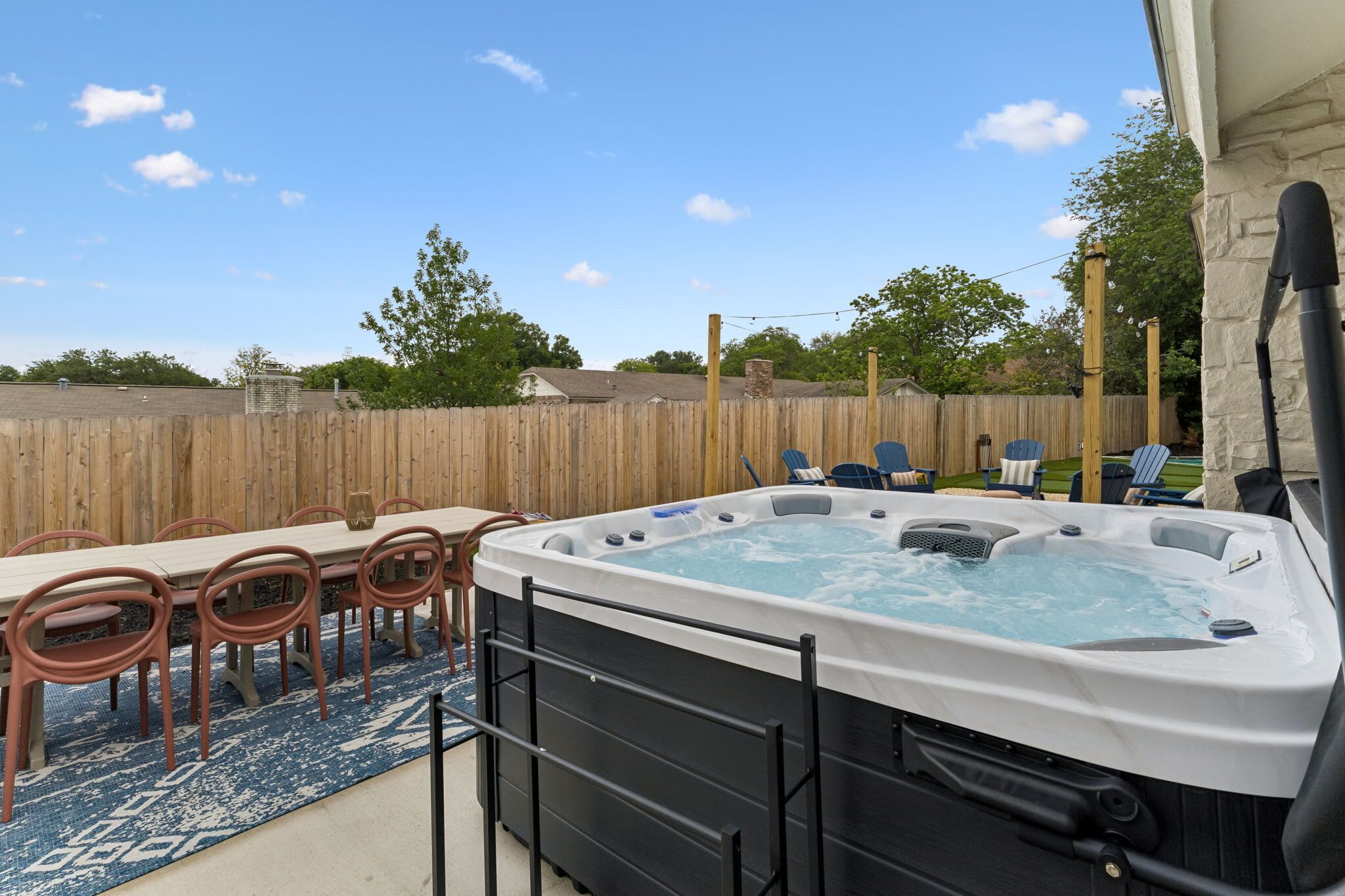 Un bain à remous avec une table et des chaises, une clôture en bois et un ciel dégagé.