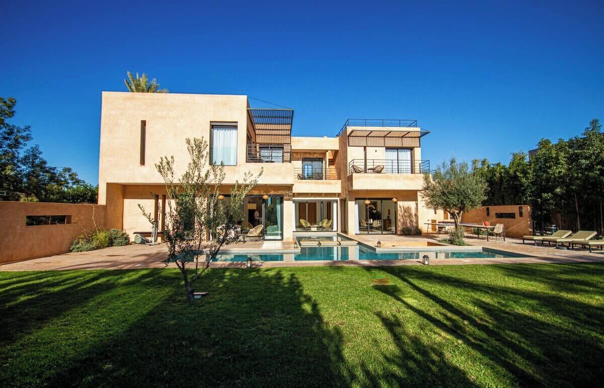 A modern two-story house with a swimming pool, outdoor seating, and a well-maintained lawn.