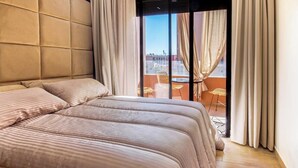 Una habitación de hotel con una cama grande, un balcón con vistas y una silla afuera.