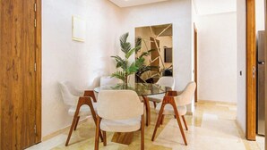 Un comedor con una mesa de vidrio, cuatro sillas, una planta en maceta y una puerta de madera.