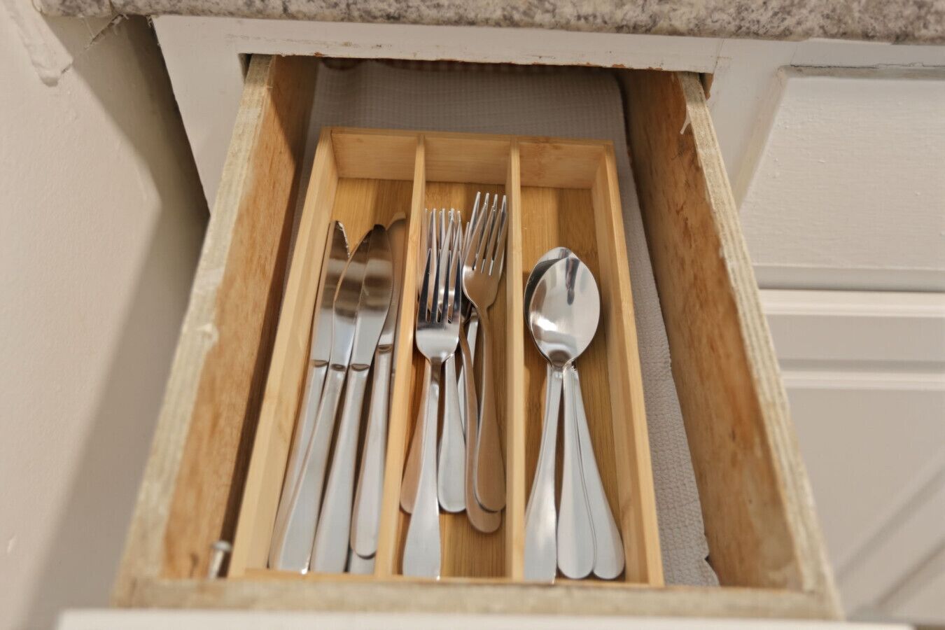 A drawer with a set of silverware including forks, knives, and spoons.